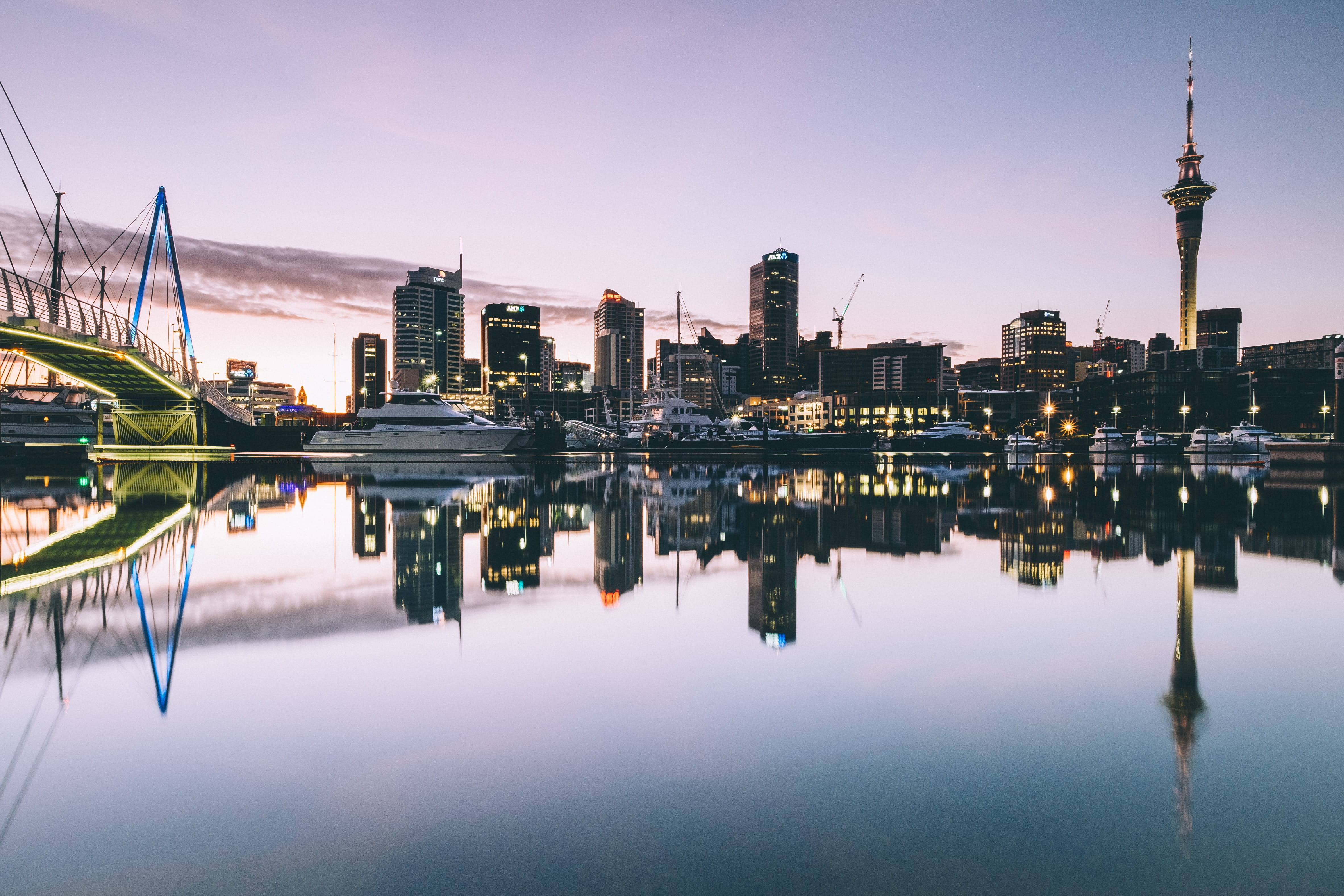 SkyCity Auckland’s SkyTower reaches into the paling twilight sky. The water is completely still and reflects, in perfect symmetry, the Auckland Waterfront’s bridge, boats and buildings surrounding it.