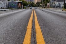 Two rich yellow lines trace down the middle of a bitumen road. Tulsa’s city skyline rises in the background. There’s a feeling of a small town having grown into a city.